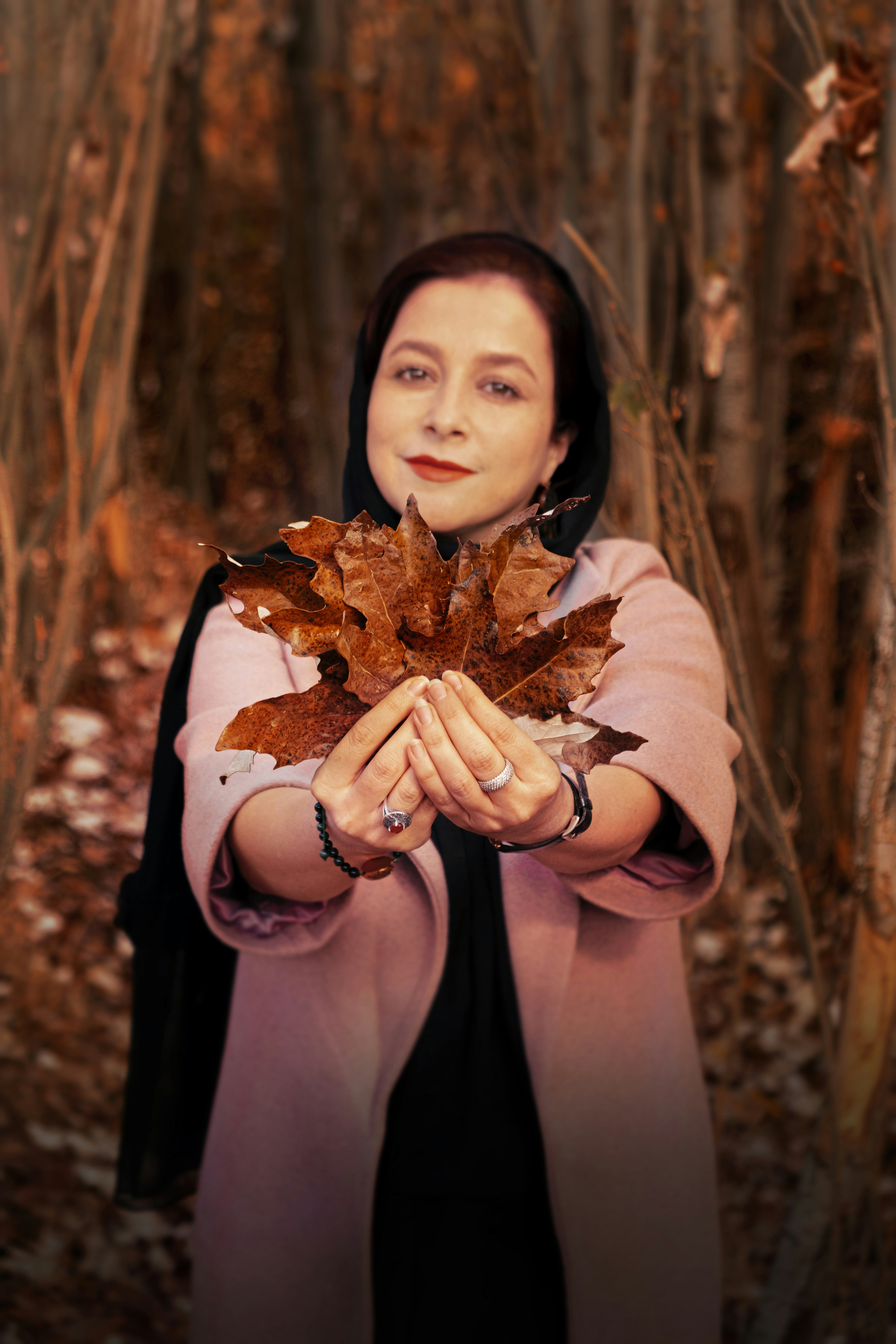 woman in brown long sleeve shirt holding dried leaves